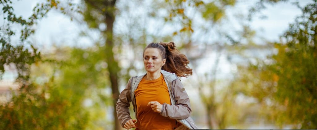 Hello autumn. young female in fitness clothes in the park running.