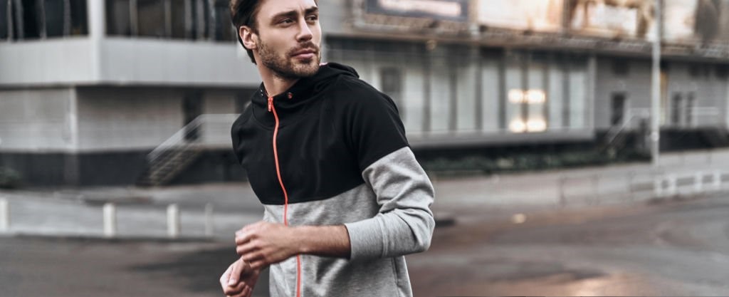 Handsome young man in sport clothing looking away while running outdoors